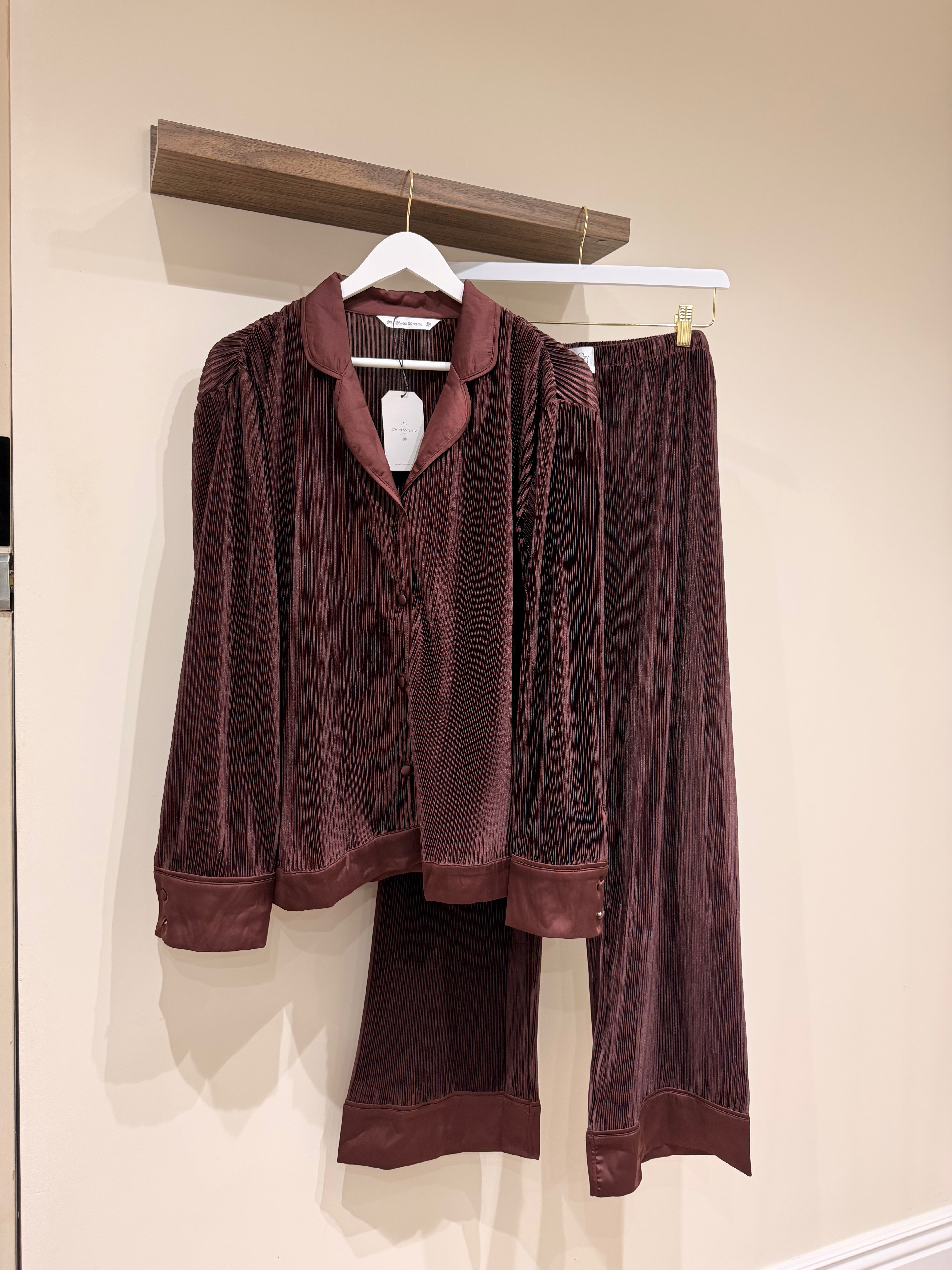 Brown plisse pajama set hanging on a rack against a beige wall.
