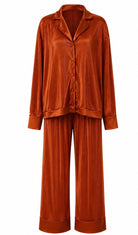 A two-piece matching pajama set in a rich rust-orange color, featuring a long-sleeve button-up shirt and wide-leg trousers, both with a vertical pleated texture, shown against a plain white background.