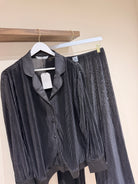 black nightwear on a wooden rack against a beige wall.