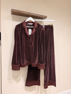 Brown plisse pajama set hanging on a rack against a beige wall.