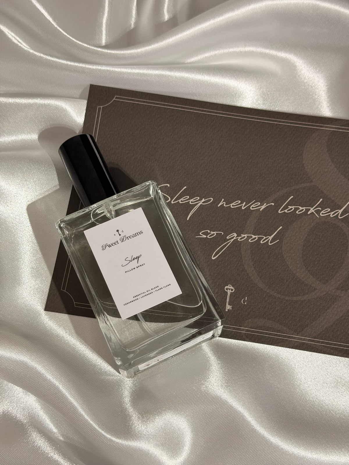 Perfume bottle labeled 'Sleep' on a satin surface with a decorative box.